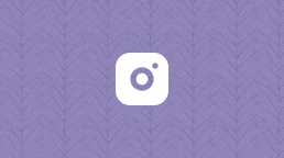 A white camera icon with a small dot on the top right is centered on a purple background featuring a subtle leaf pattern.
